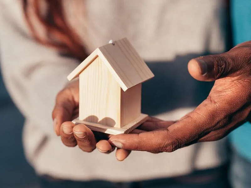 casa de madera en las manos de un hombre